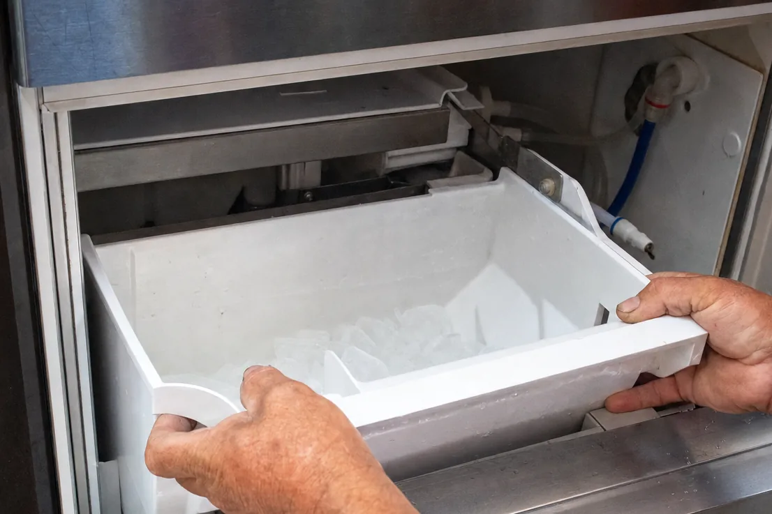 Close view of the white ice mould and bin inside a stainless machine cabinet