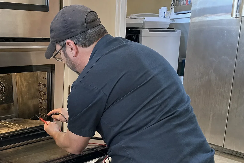 A built-in oven standing open in a newer kitchen, cabinetry either side of the opening